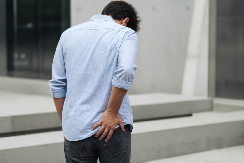 Homme en chemise bleue tenant sa fesse gauche